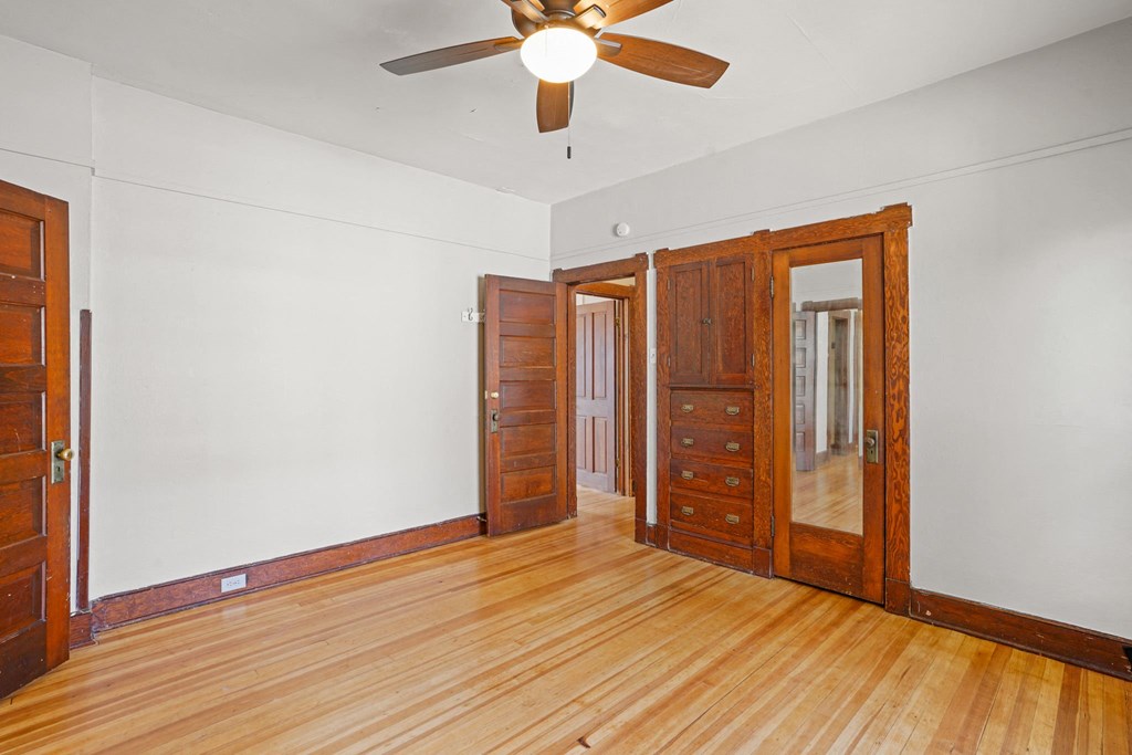 A room with a ceiling fan and wooden floors.