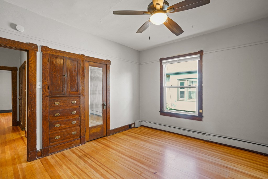 A room with a ceiling fan and a wooden floor.