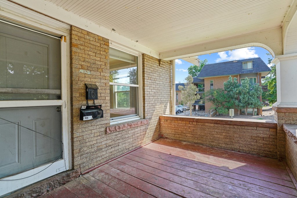 A balcony with a brick wall and a wooden floor.