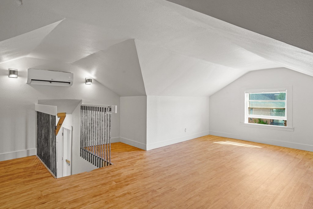 A room with wooden floors and a window with a view of a body of water.