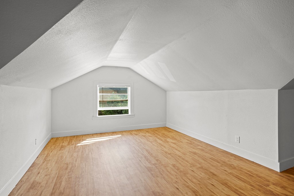 A room with a window and wooden floors.
