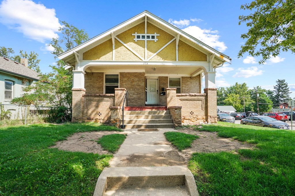 A yellow house with a white porch and a small front yard.