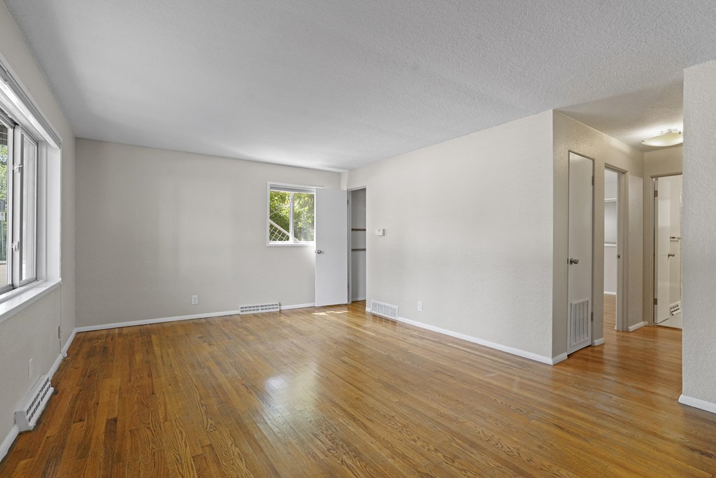 a bedroom with hardwood floors and white walls