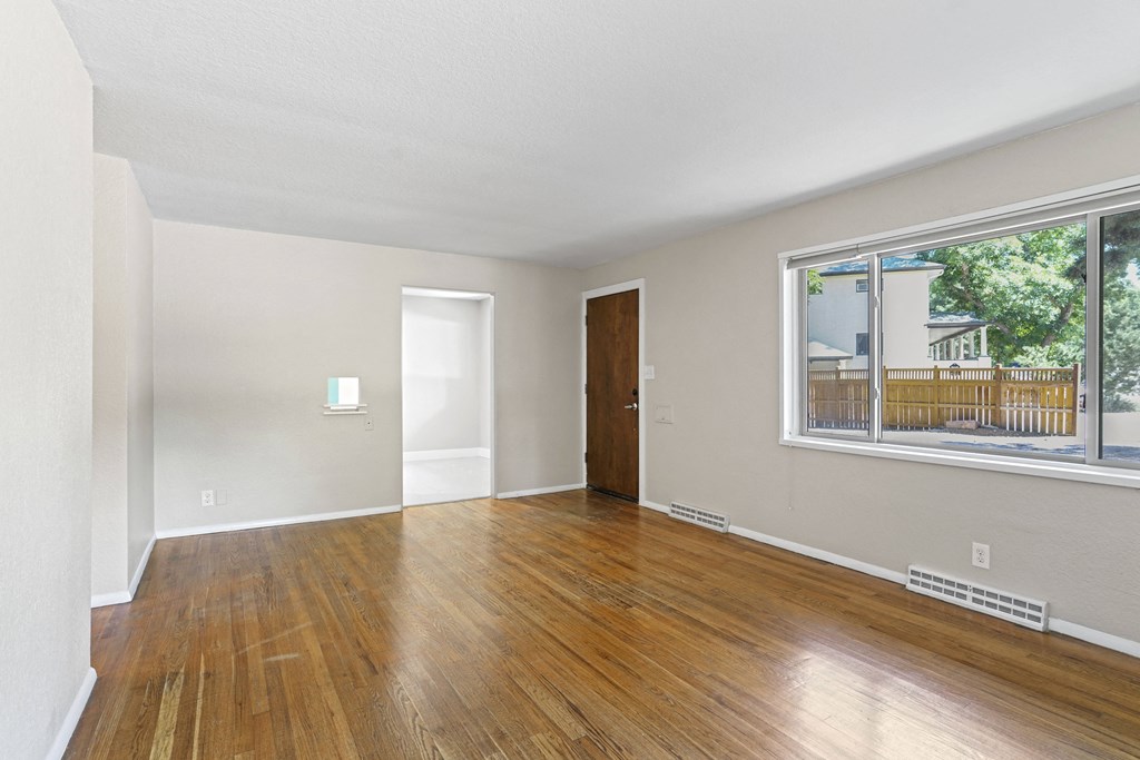 a living room with hardwood floors and a large window
