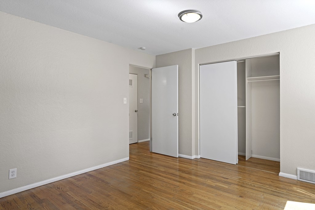 a bedroom with hardwood floors and white walls