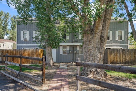 A grey house with a tree in front of it.