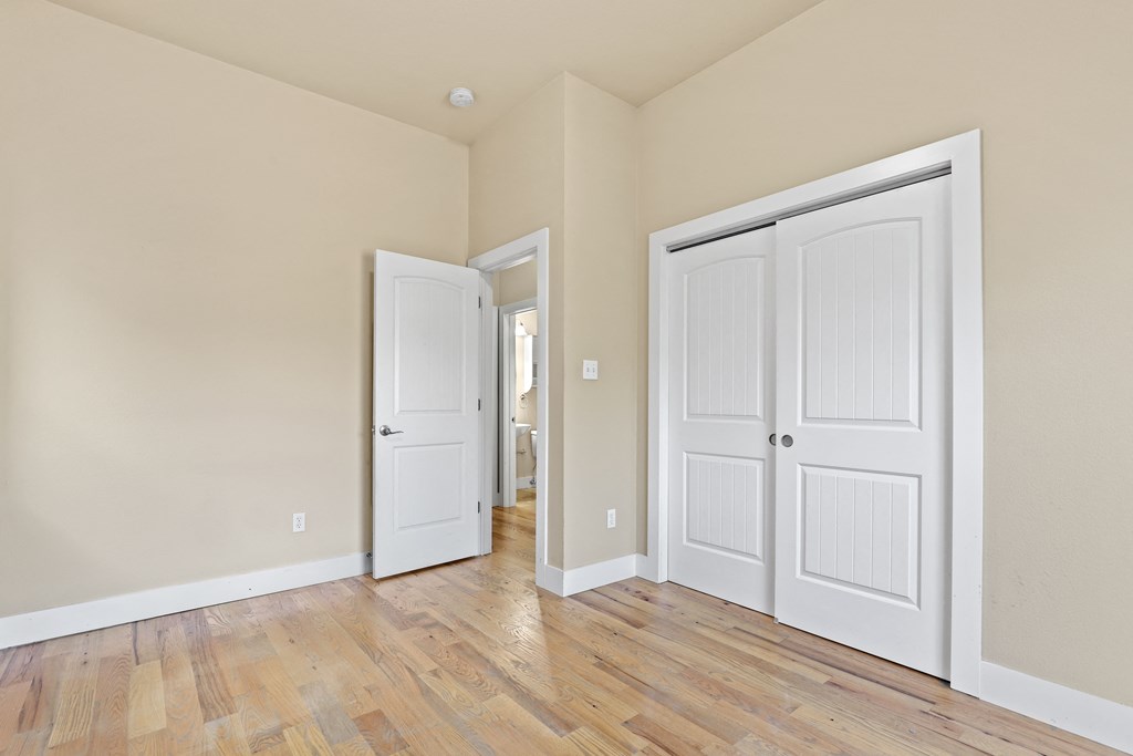 a bedroom with two doors and a hallway in the background