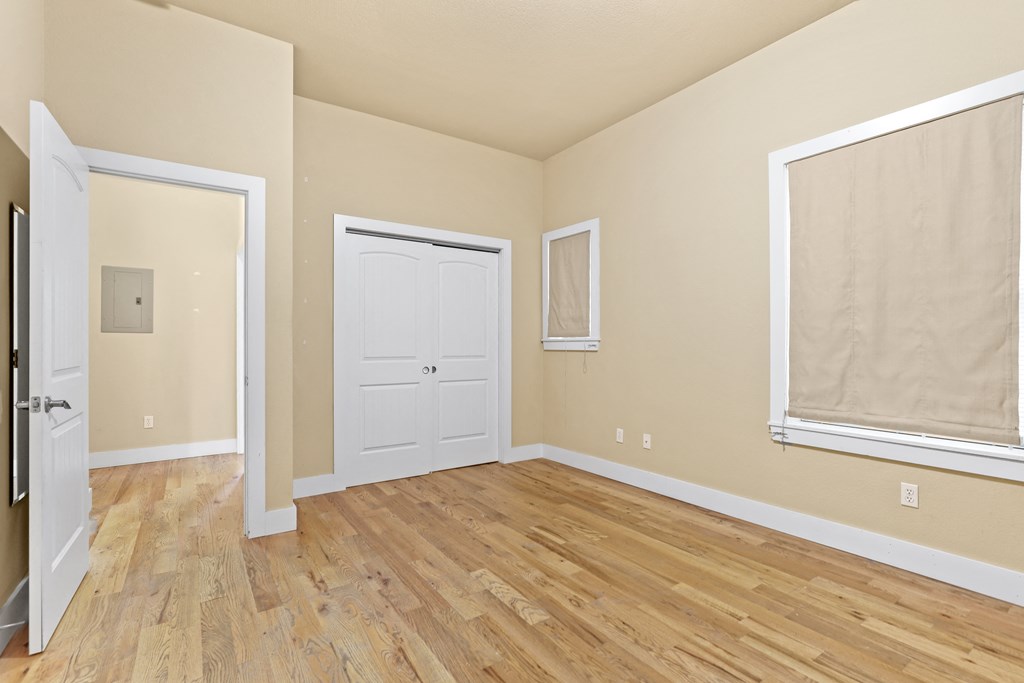 a bedroom with hardwood floors and a white door
