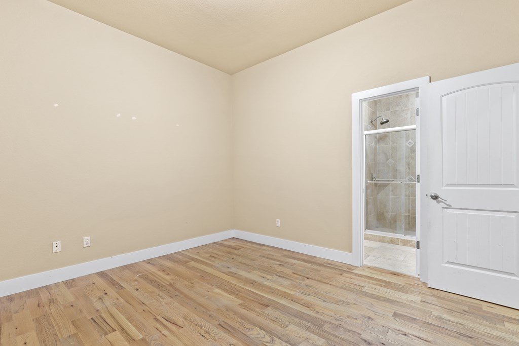 a bedroom with hardwood floors and a white door