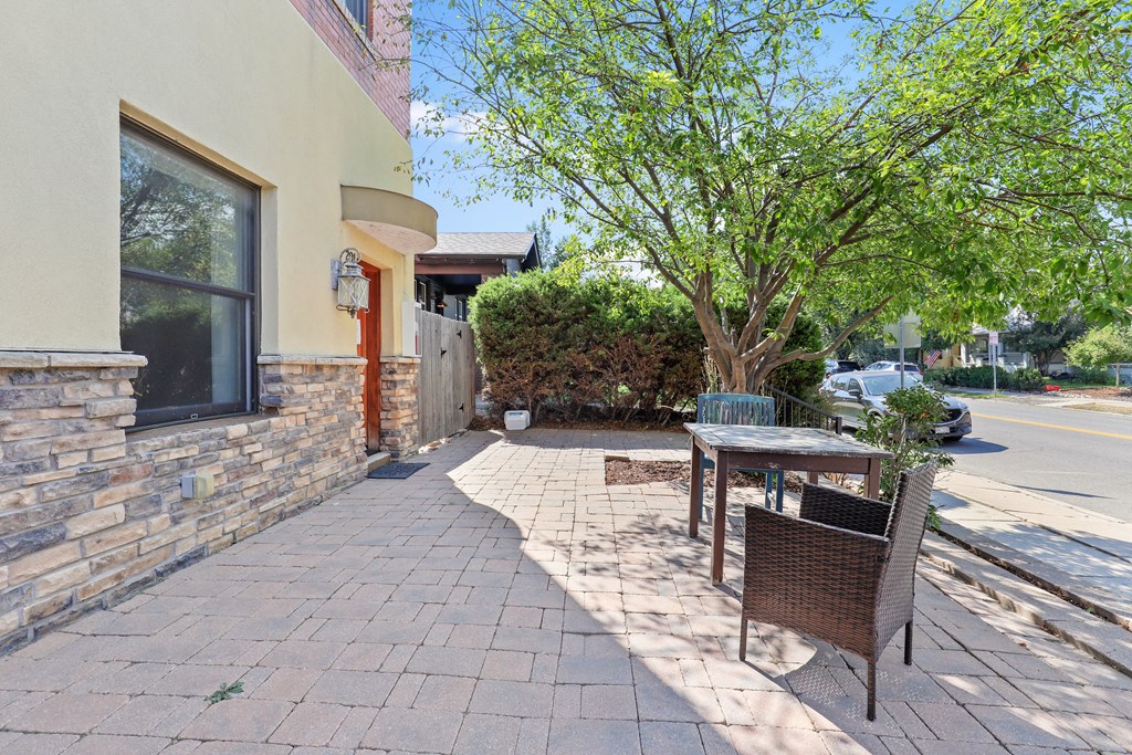 a patio with a table and chairs in front of a building