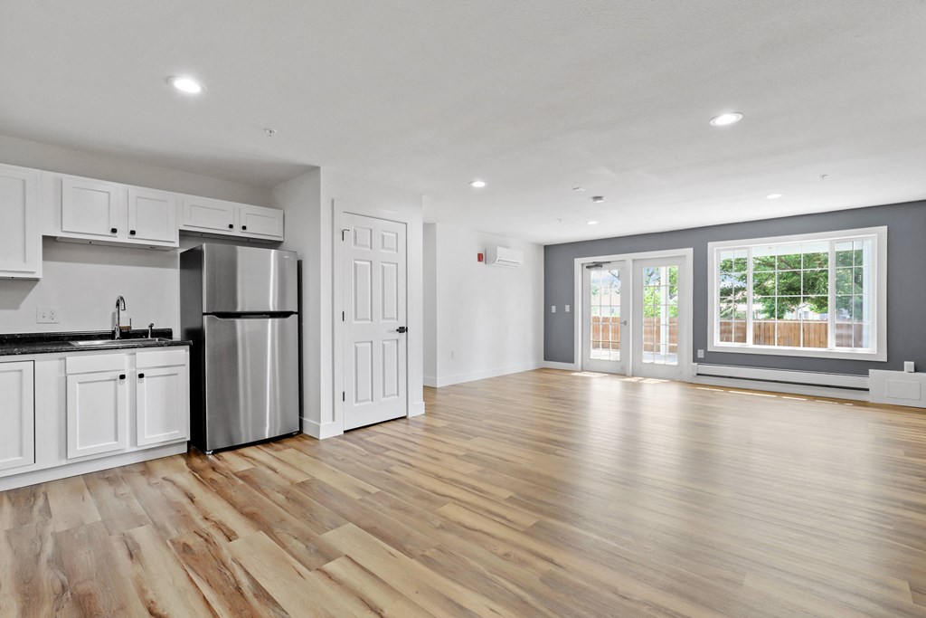a kitchen and living room with white walls and wood floors