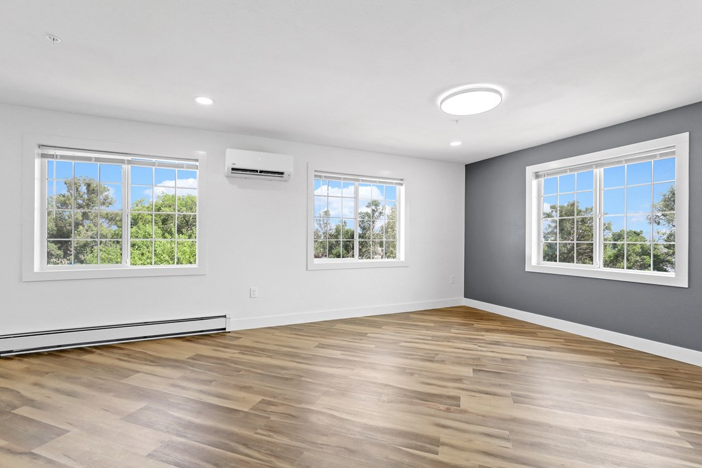 an empty room with hardwood floors and three windows