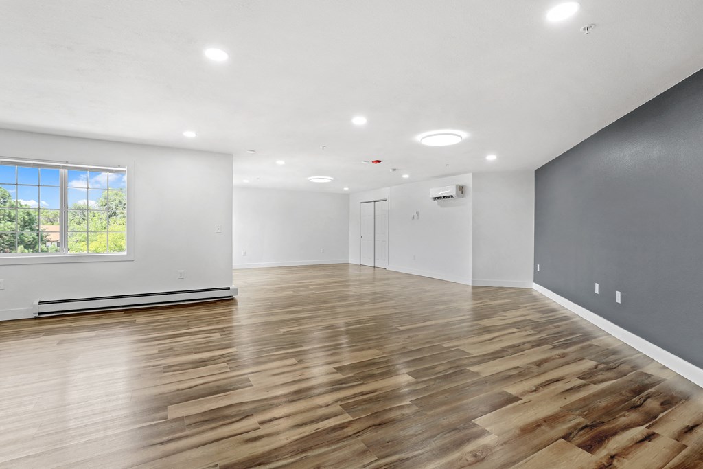 the living room with hardwood floors and a large window
