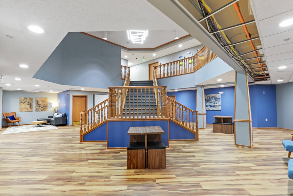 a large staircase in the center of a large room with wood floors and blue walls