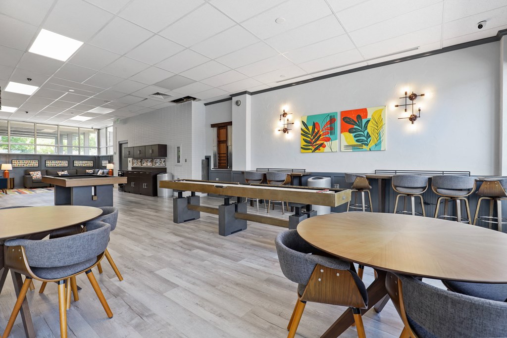 a room with tables and chairs and a bar in the background