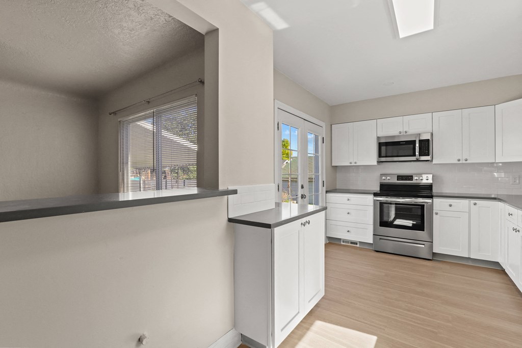 an empty kitchen with white cabinets and stainless steel appliances