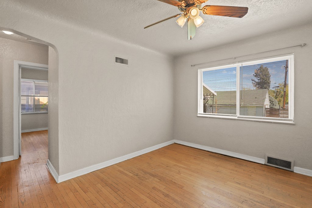 an empty living room with a ceiling fan and a window
