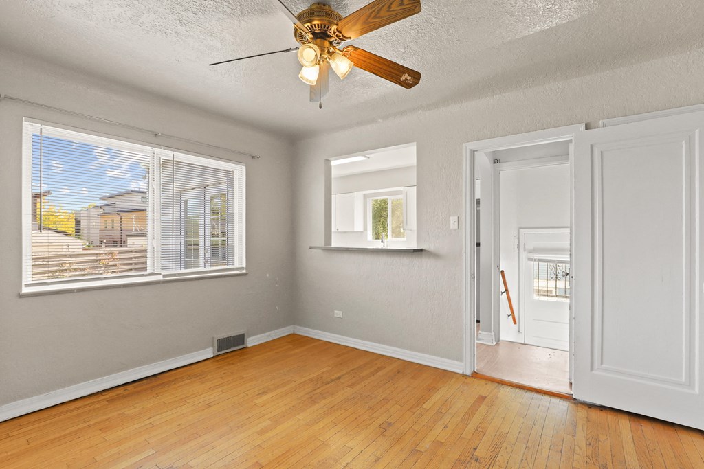 an empty living room with a ceiling fan and a door to a hallway