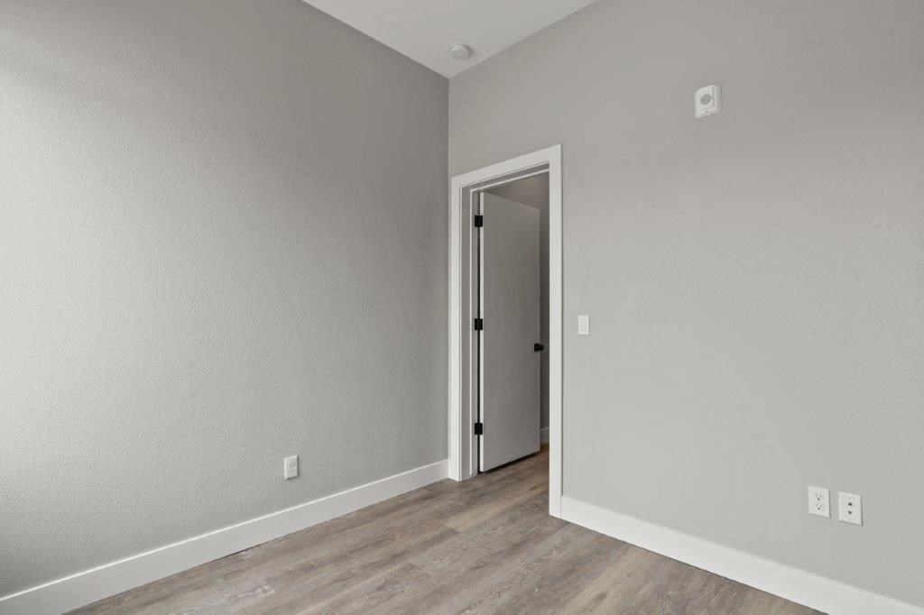 a bedroom with wood floors and a door to a closet