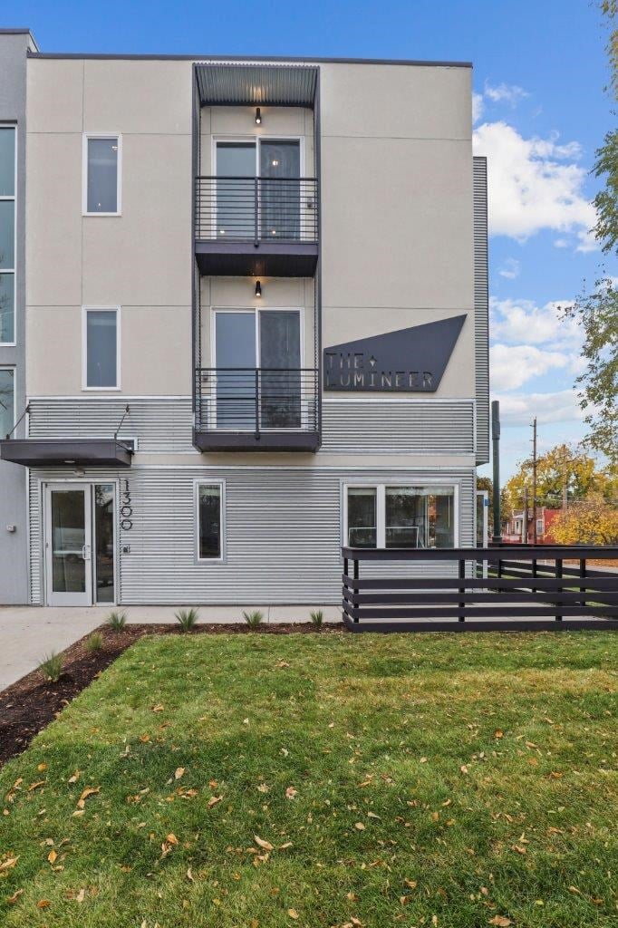 the front of a building with a yard and a deck