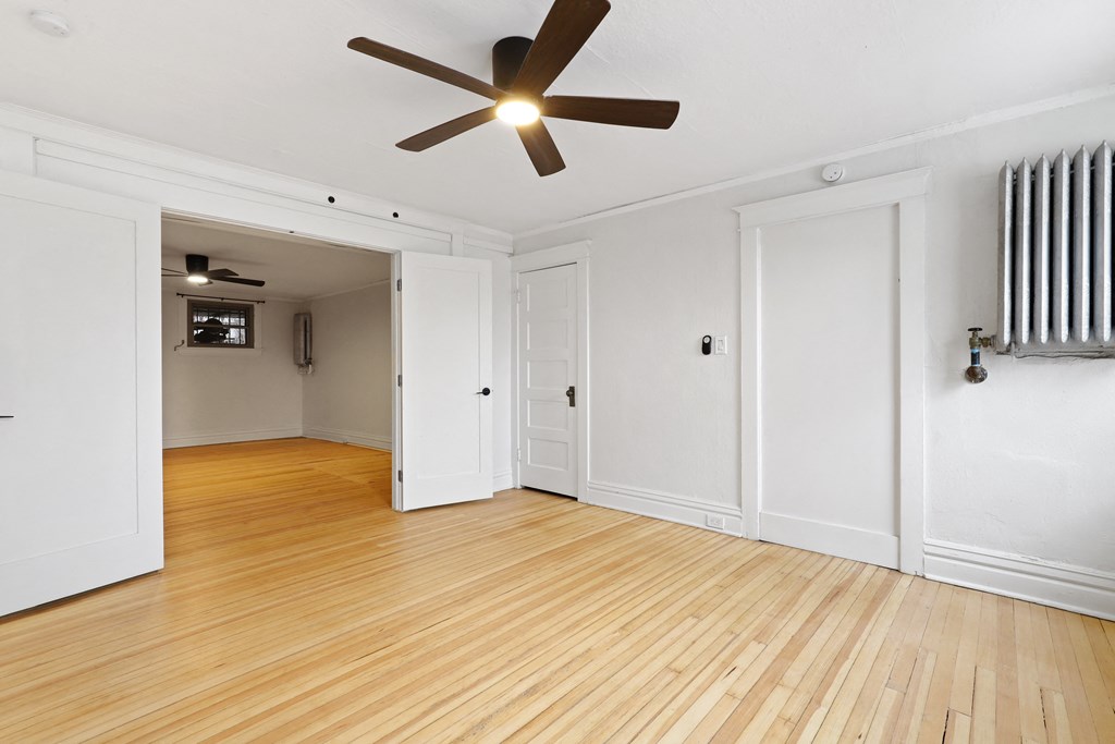 an empty living room with white walls and a ceiling fan