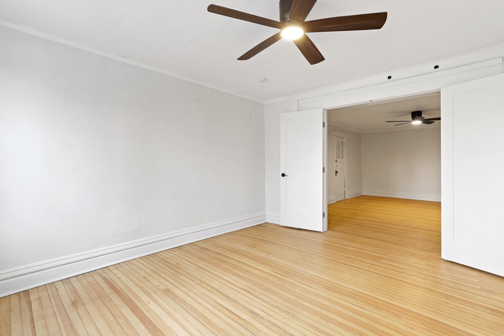 an empty living room with wood floors and a ceiling fan