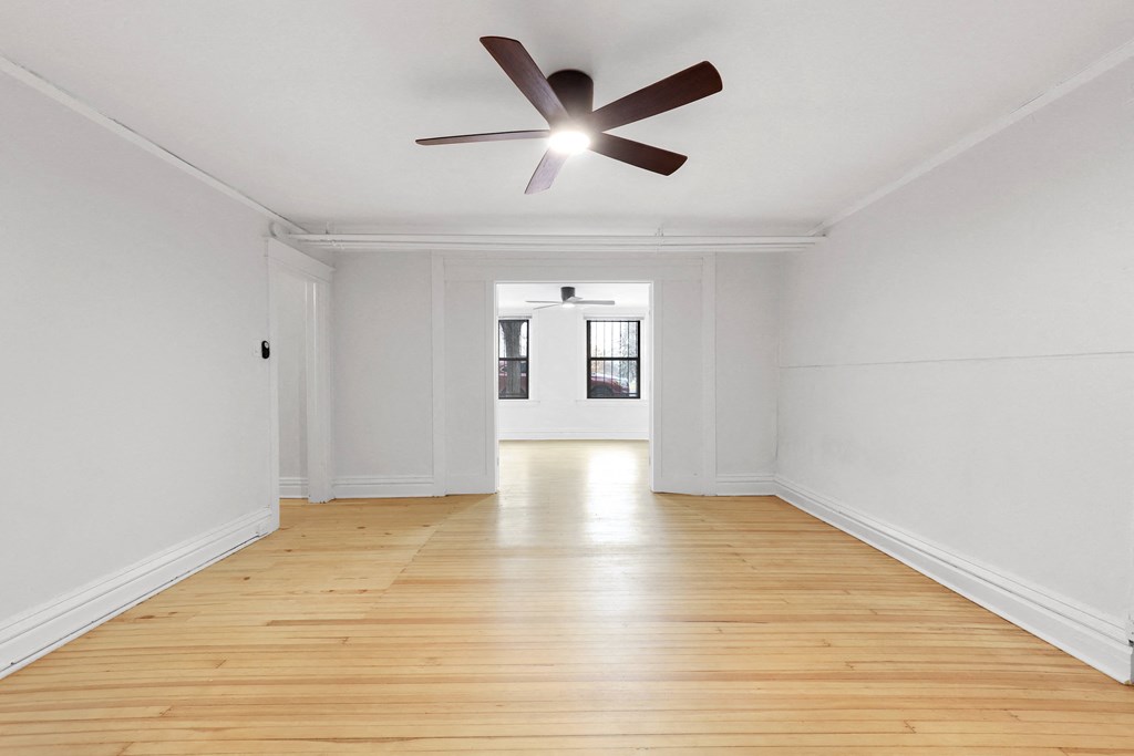 a living room with white walls and wood floors and a ceiling fan