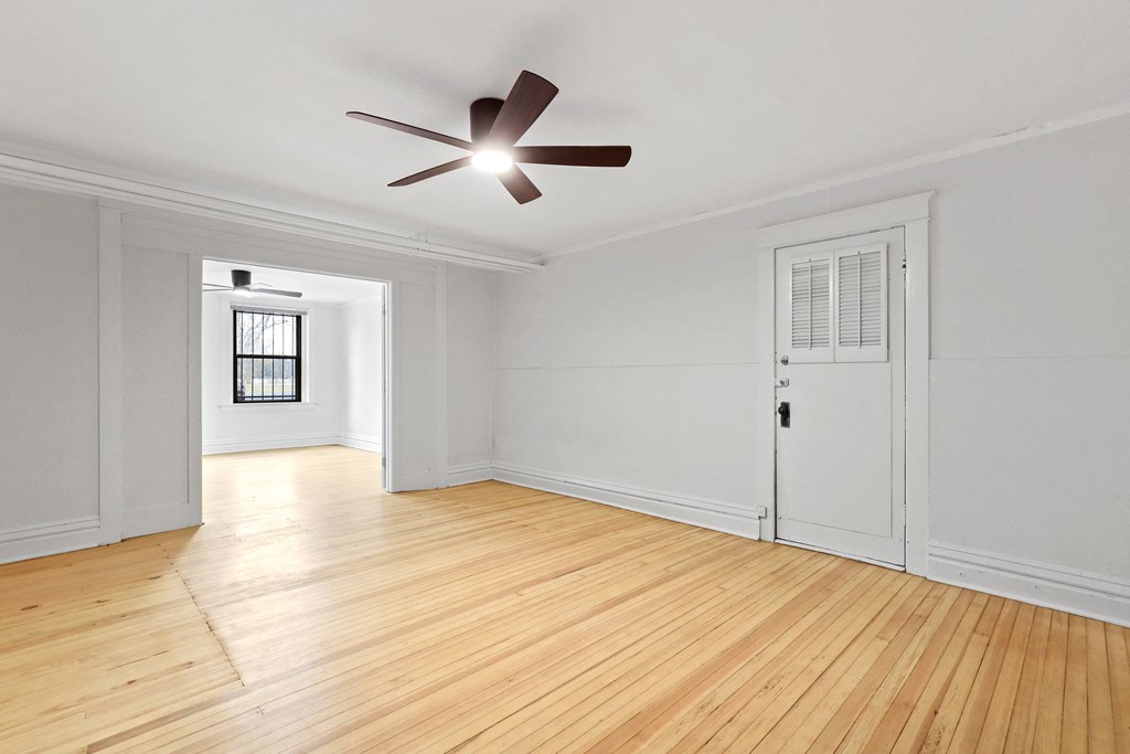 an empty living room with white walls and a ceiling fan