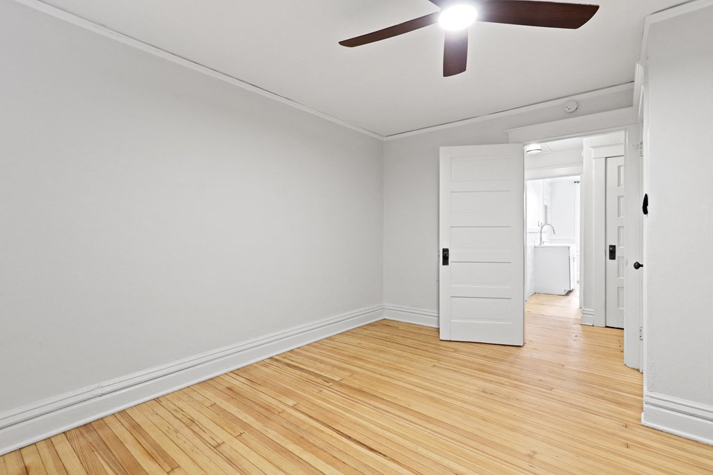 an empty room with wood floors and a ceiling fan