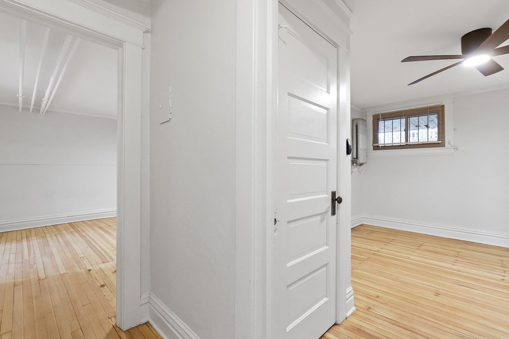 a living room with a white door and a ceiling fan