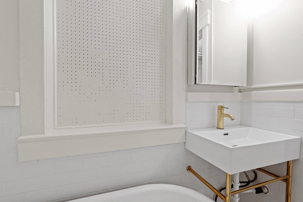 a white bathroom with a sink and tub and a mirror