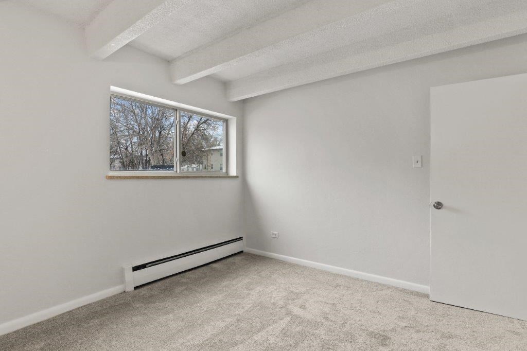 an empty bedroom with a window and a door