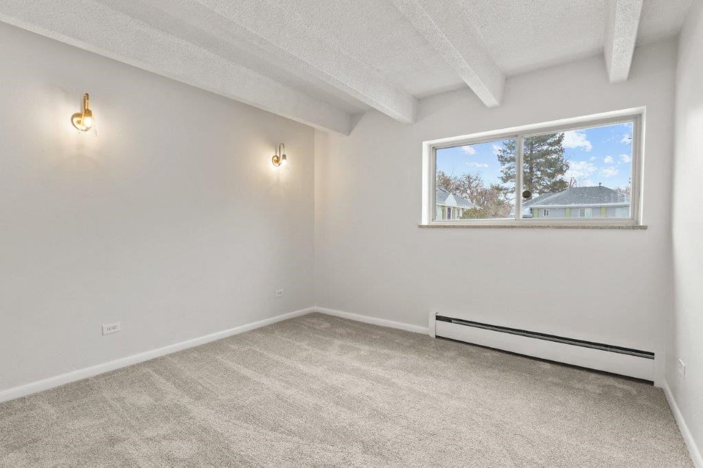 an empty living room with a window and a carpet