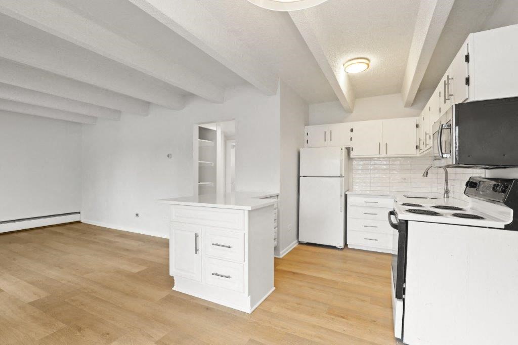 an empty kitchen with white cabinets and a stove and refrigerator