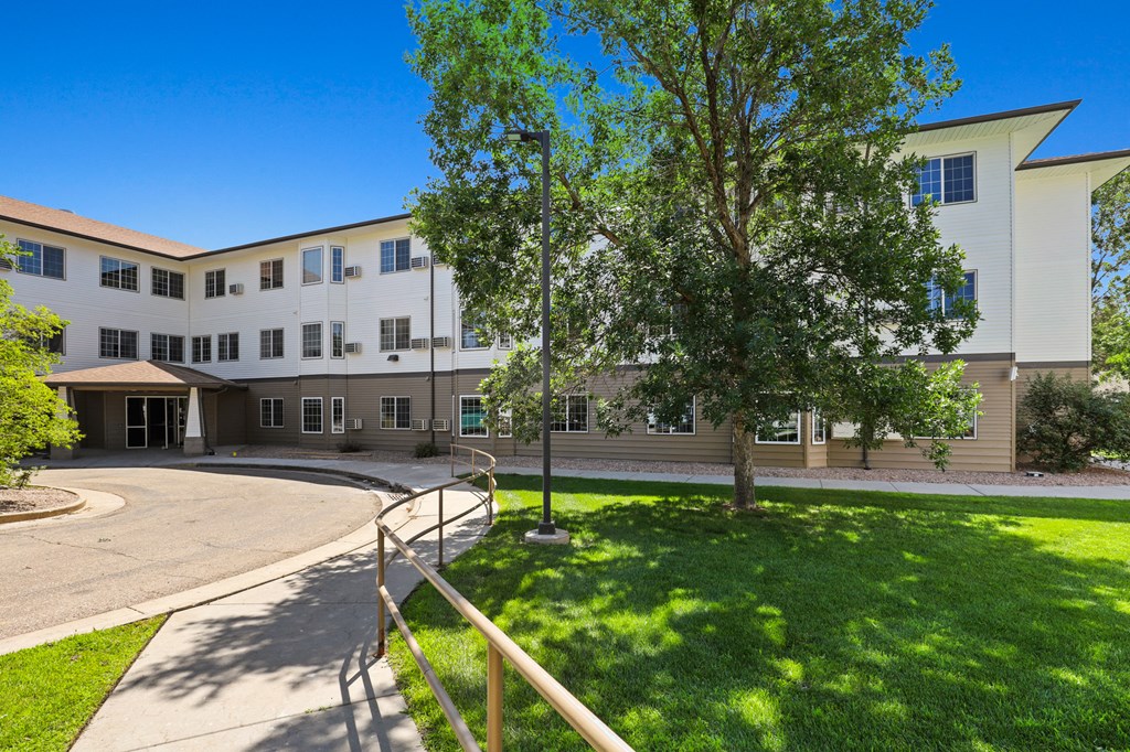 a large white building with trees and a yard in front of it