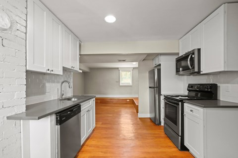 A kitchen with white cabinets and a wooden floor.