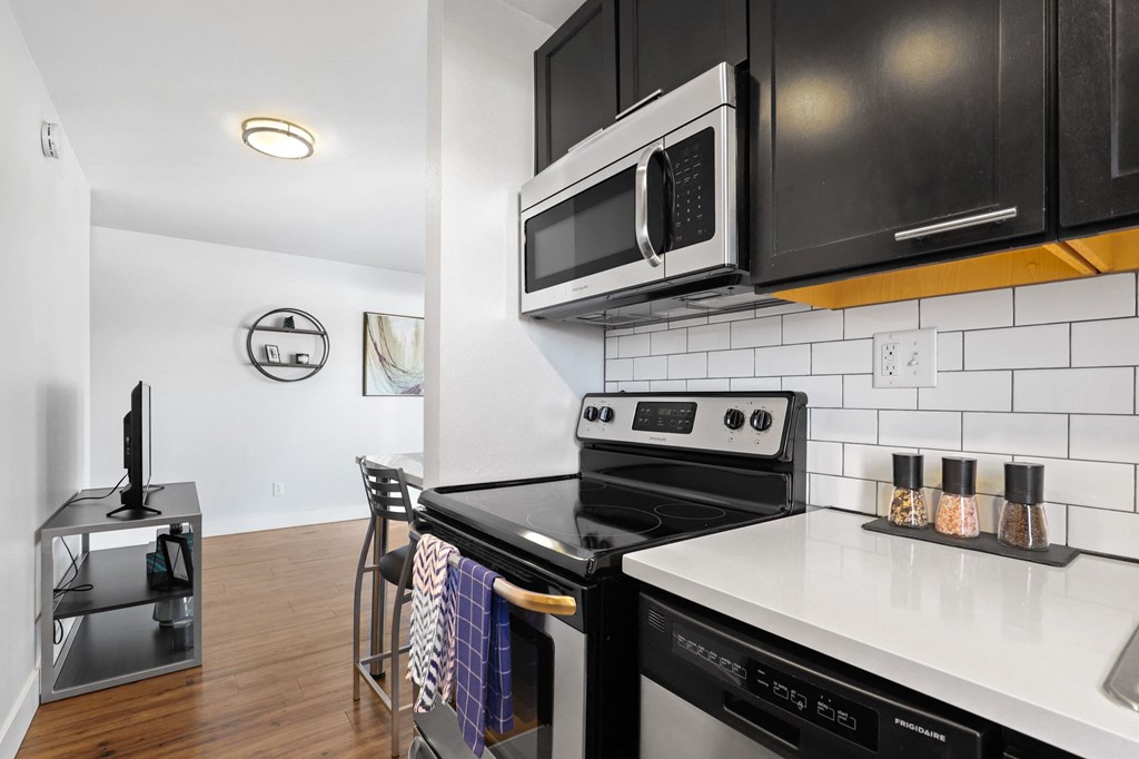 a kitchen with black appliances and white counter tops and black cabinets