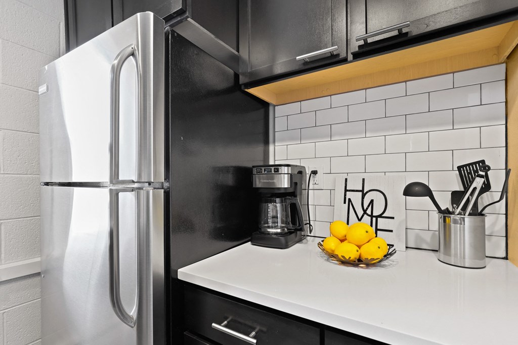 a kitchen with black cabinets and a stainless steel refrigerator