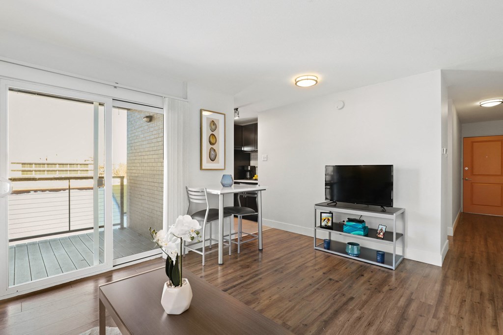 a living room with a tv and a table with chairs   and a balcony