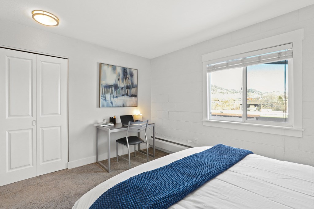 a bedroom with a bed and a desk with a window