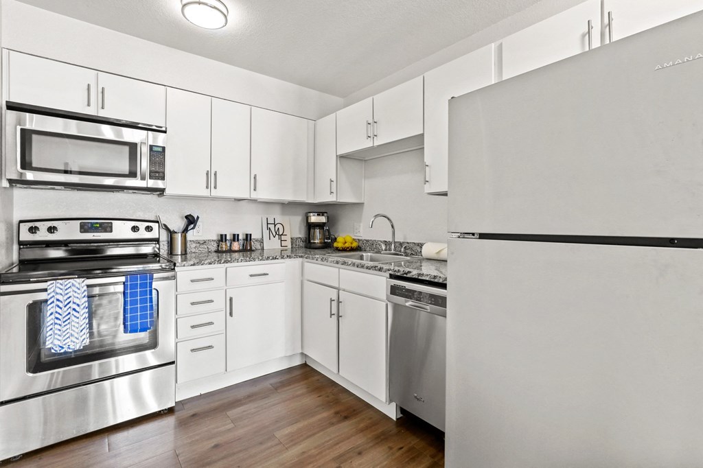 an empty kitchen with stainless steel appliances and white cabinets
