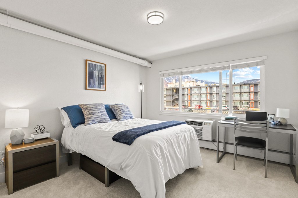 an apartment bedroom with a bed and a large window