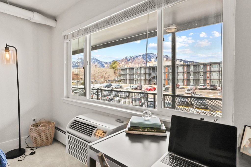 a home office with a desk and a window with a view of a city street