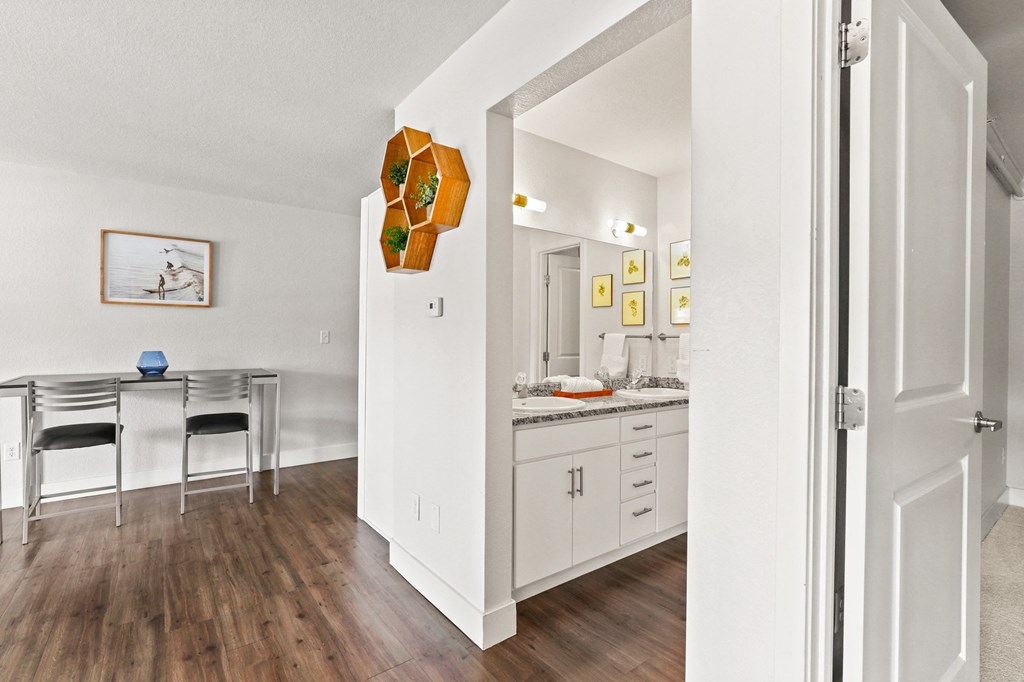 the living room and dining room of a house with white walls and wood flooring