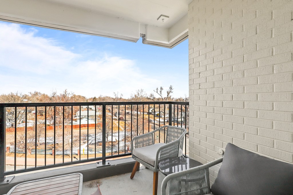 the balcony of a condo with chairs and a balcony railing