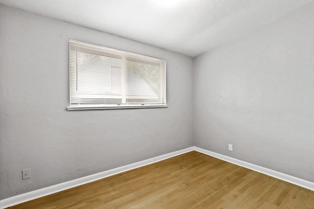 a bedroom with a window and hardwood floors