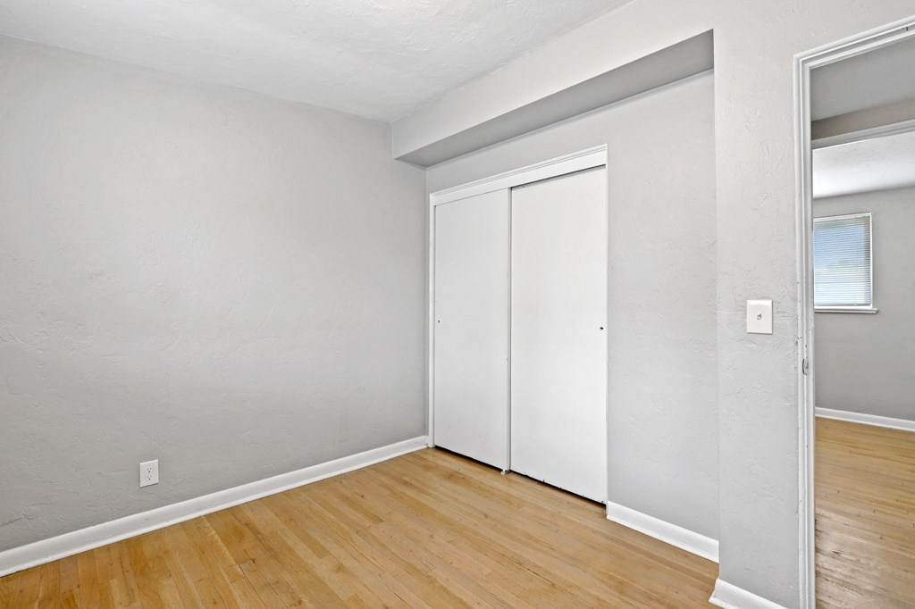 a bedroom with hardwood floors and grey walls