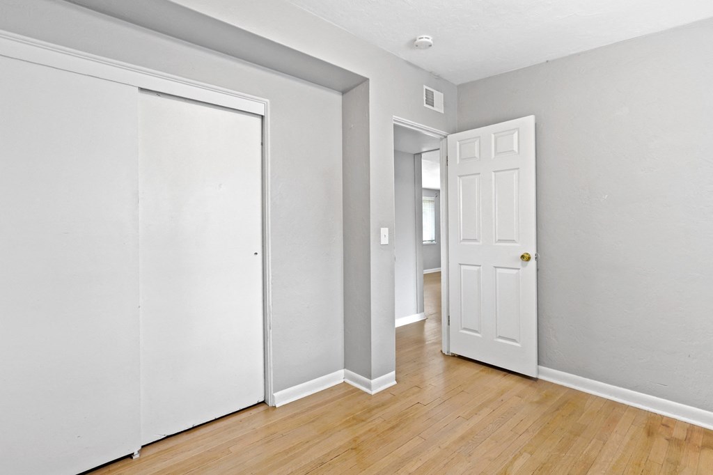 a bedroom with two doors and a hardwood floor