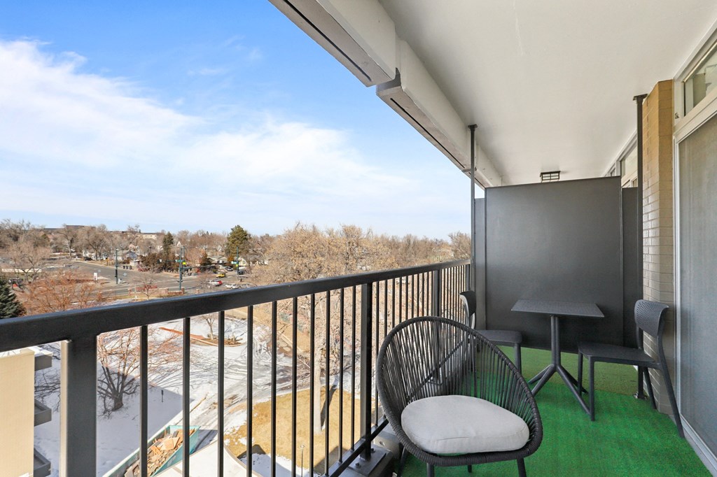 a balcony with two chairs and a table and a view of the city
