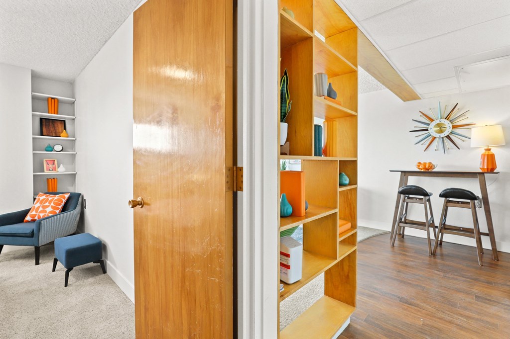 a living room with a door to a closet and a desk with a chair